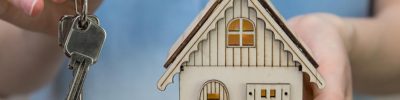 Woman holding key and small model house
