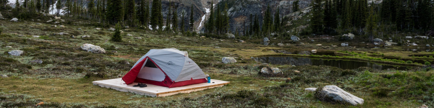 tent camped by a small lake amongst mountain scenery
