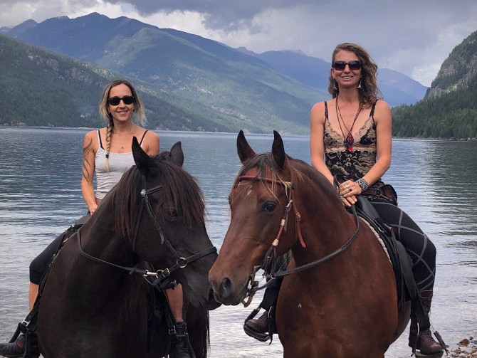 Two women on horseback by lake