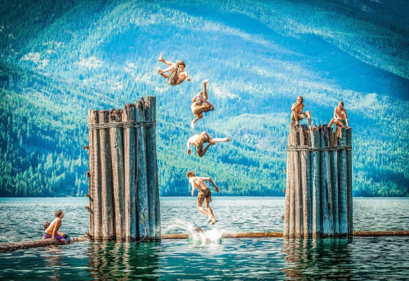 man jumps into lake off logs